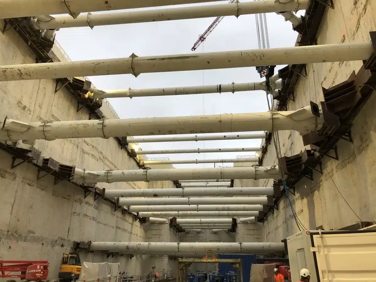 Soutènement par étrésillons métalliques blancs dans une excavation profonde sur un chantier de génie civil.